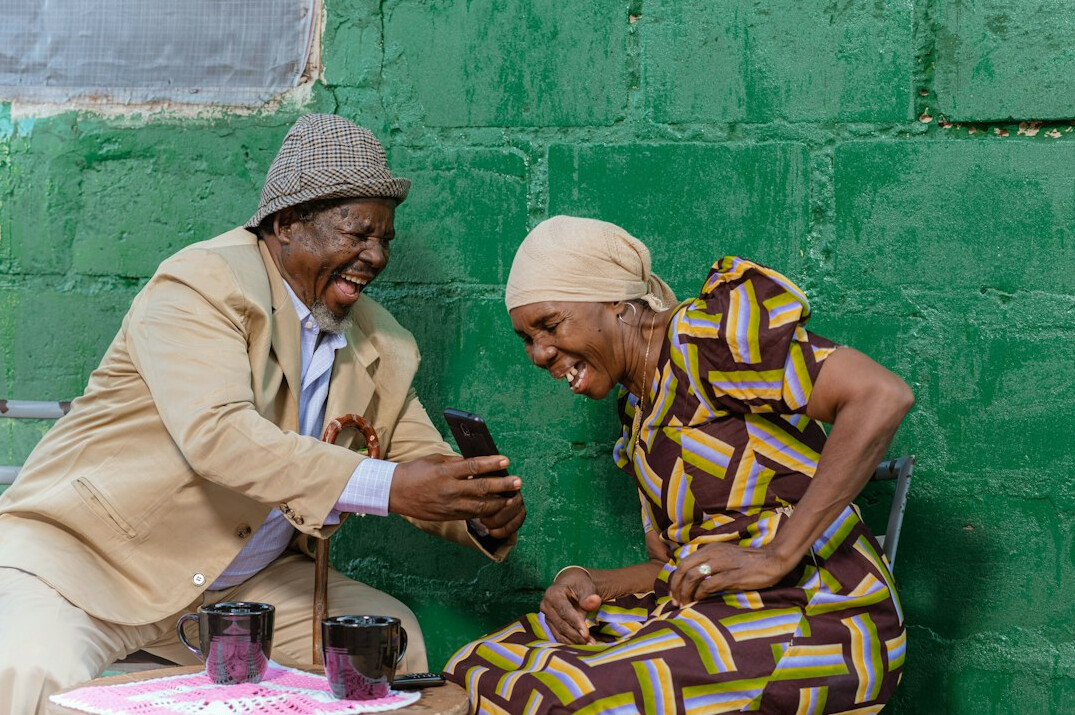 Group of cheerful senior friends laughing together at a table in a bright community room